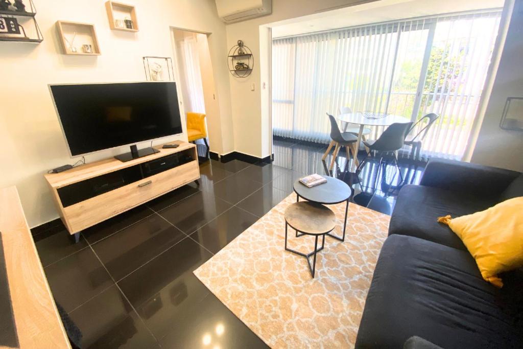 un salon avec un canapé, une télévision et une table dans l'établissement Cosy 2 pièces - Palais Croisette Cannes, à Cannes