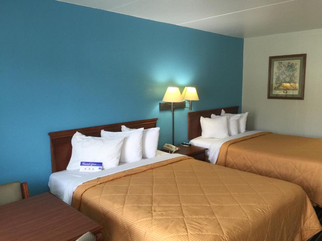 twee bedden in een hotelkamer met blauwe muren bij American Inn Morrilton in Morrilton