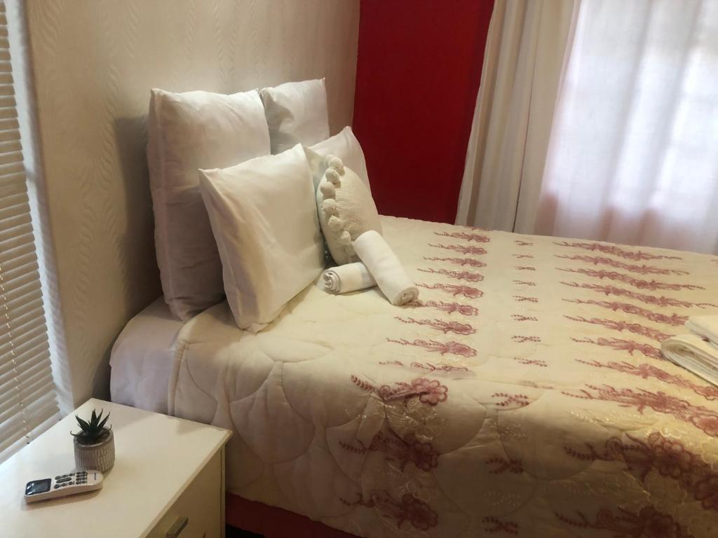 a bedroom with a bed with pillows and a table at The Legacy in Mochudi