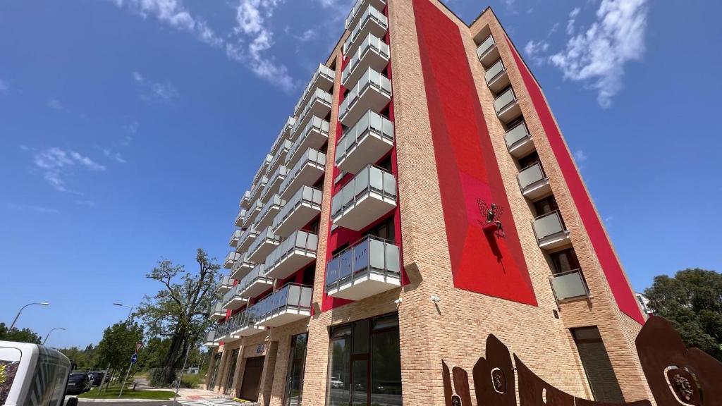 un grand bâtiment en briques avec une façade rouge dans l'établissement 2 room Apartment, new building, Bosákova street, 49, à Bratislava