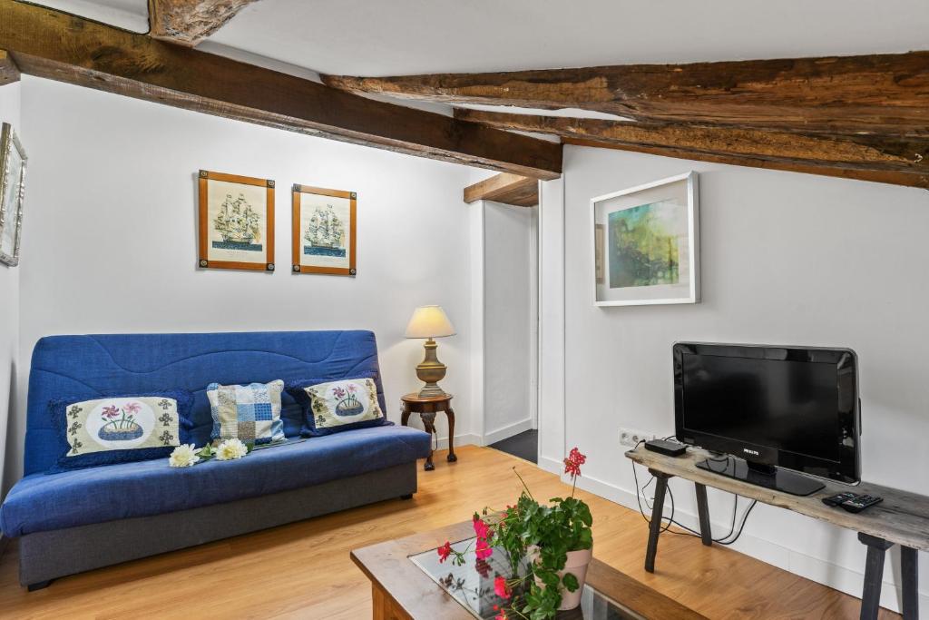 un salon avec un canapé bleu et une télévision dans l'établissement Apartamento 2, à Selores