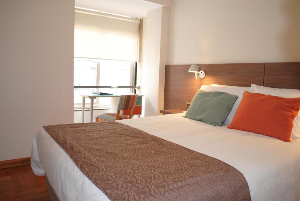 1 dormitorio con 1 cama grande con almohadas de color naranja y verde en Hotel Santa Lucia, en Santiago