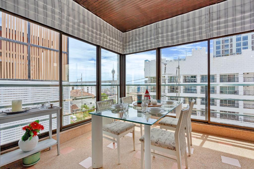 a dining room with a table and chairs and windows at Grosvenor House - Olympic Pool - Pattaya in Pattaya South