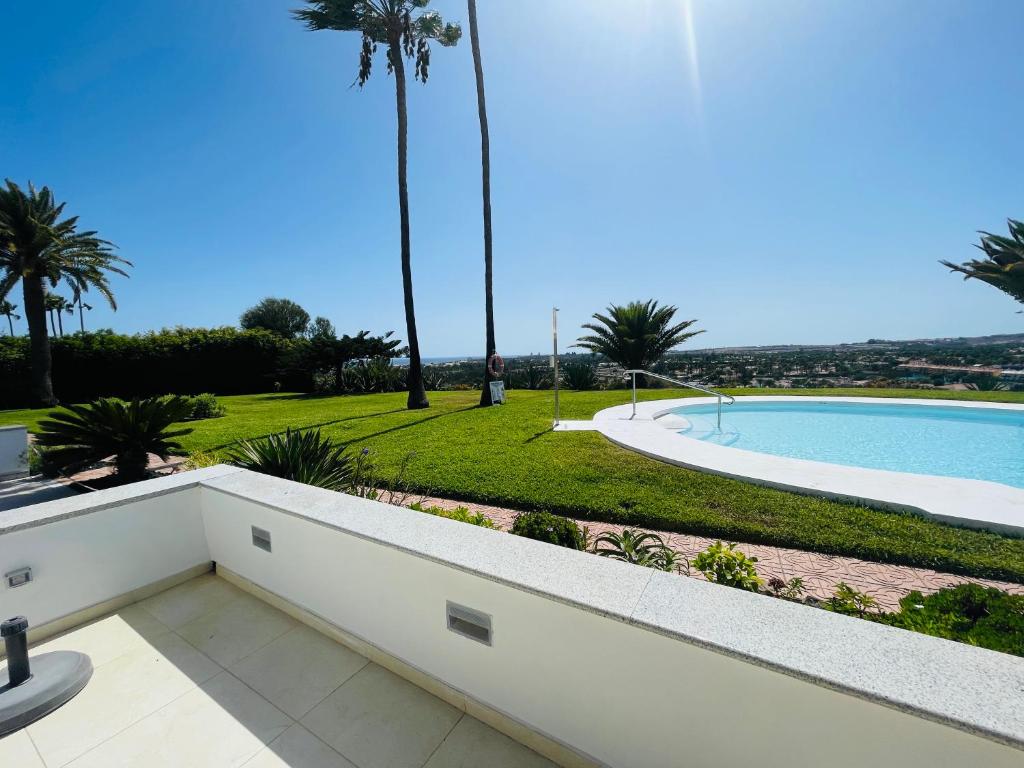 a villa with a swimming pool and palm trees at Seaview Bungalow Duna Golf in Playa del Ingles