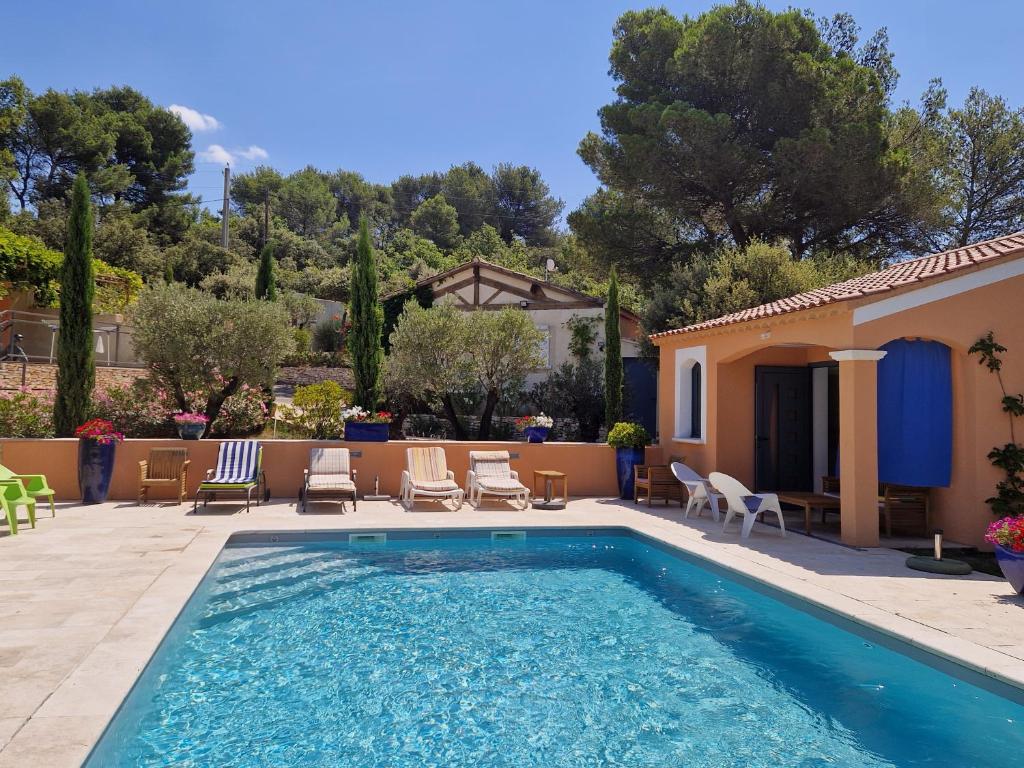 une piscine avec des chaises et une maison dans l'établissement la Cigalière, à LʼIsle-sur-la-Sorgue