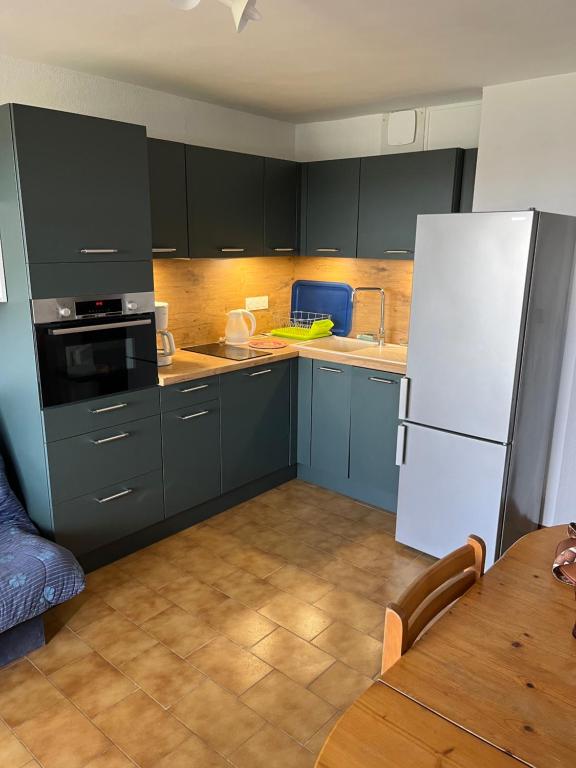 une cuisine avec des armoires bleues et un réfrigérateur blanc dans l'établissement 34300 le cap d’Agde, au Cap d'Agde