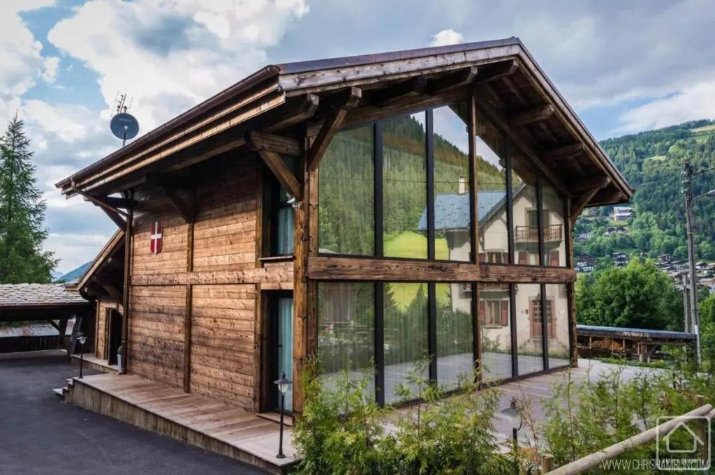 une maison en bois avec des fenêtres en verre sur une montagne dans l'établissement Chalet grandiose au pied des pistes de Morzine - Vue imprenable, à Morzine