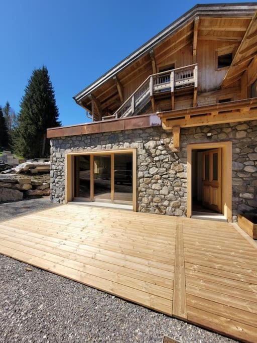 une maison avec une grande terrasse en bois devant elle dans l'établissement Appartement montagne 50m2 2 chambres et un canapé lit, aux Gets