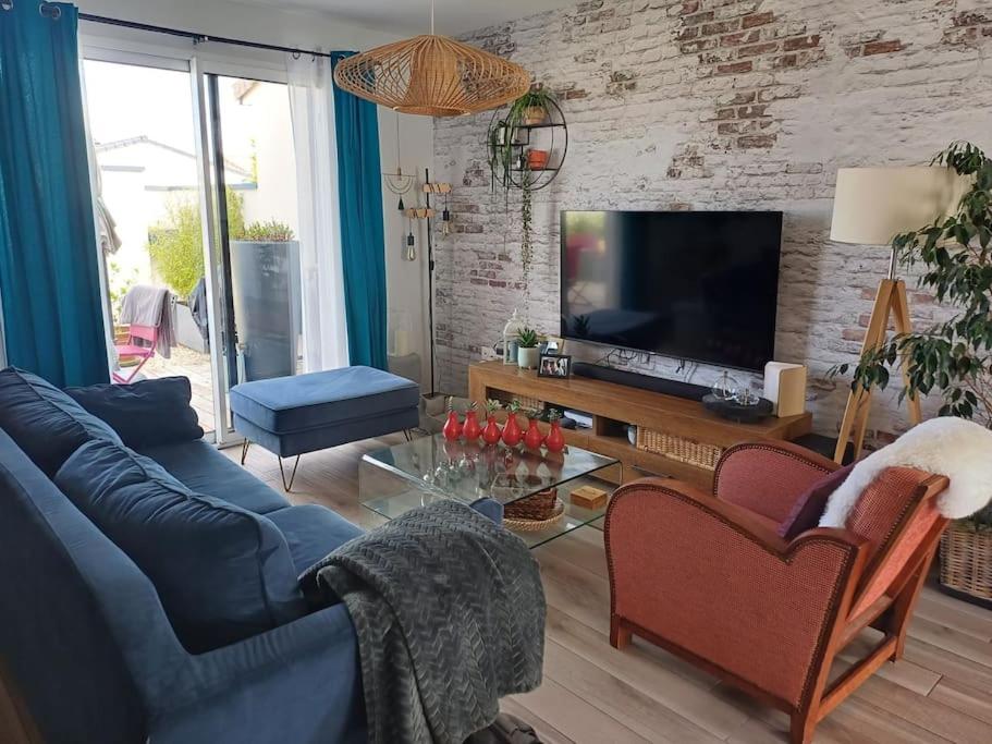 ein Wohnzimmer mit einem blauen Sofa und einem Fernseher in der Unterkunft Maison individuelle in Neuville-du-Poitou