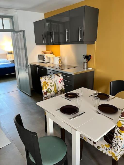 une cuisine avec une table blanche, des chaises et un comptoir dans l'établissement Appartement Remparts de Guérande, à Guérande