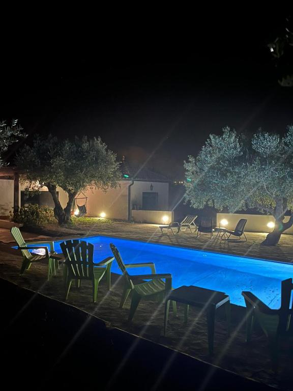 a group of chairs sitting around a swimming pool at night at Quinta Santo Antonio do Rio in Celorico da Beira