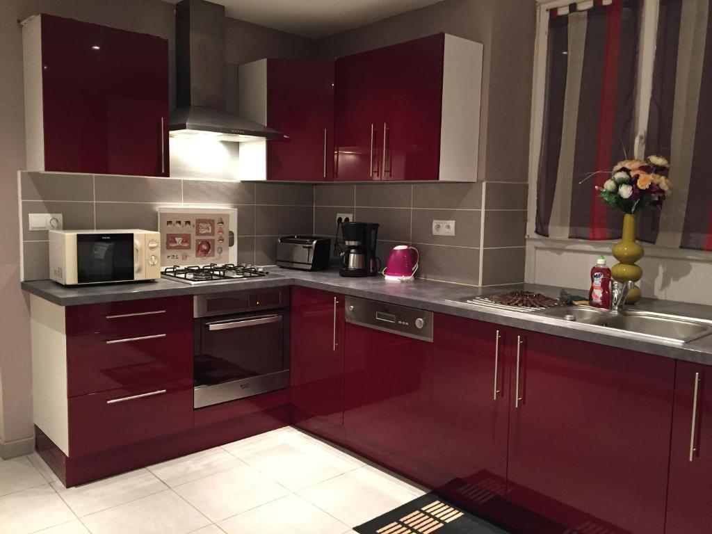 a kitchen with red cabinets and a stove top oven at Rochire Location 2 in Gérardmer