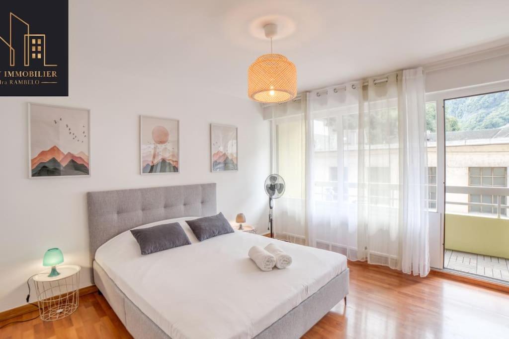 a white bedroom with a bed and a large window at Appartement Pastel in Cluses