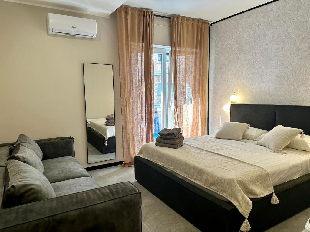 a bedroom with a bed and a couch and a mirror at Golden Palm B&B in Bari