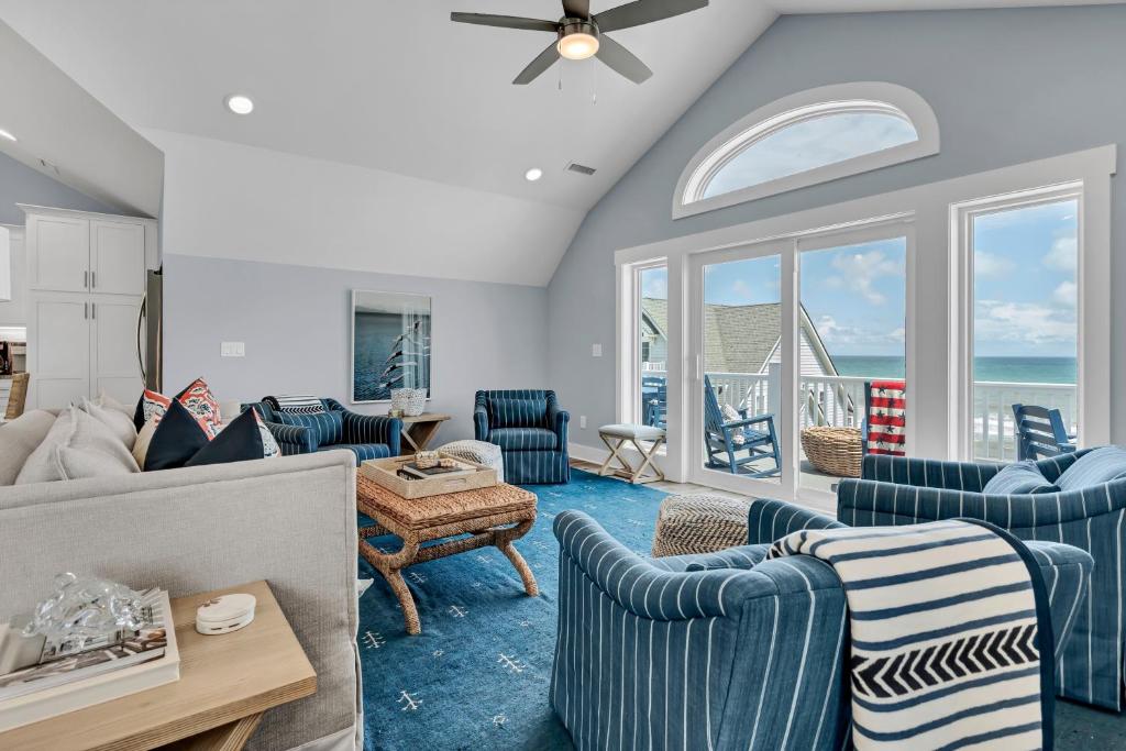 een woonkamer met blauw-witte meubels en de oceaan bij Pinewalk by Sea Scape Properties in North Topsail Beach