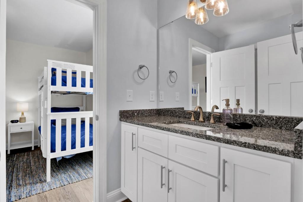 a white bathroom with a sink and a mirror at Salt Life Retreat by Sea Scape Properties in North Topsail Beach