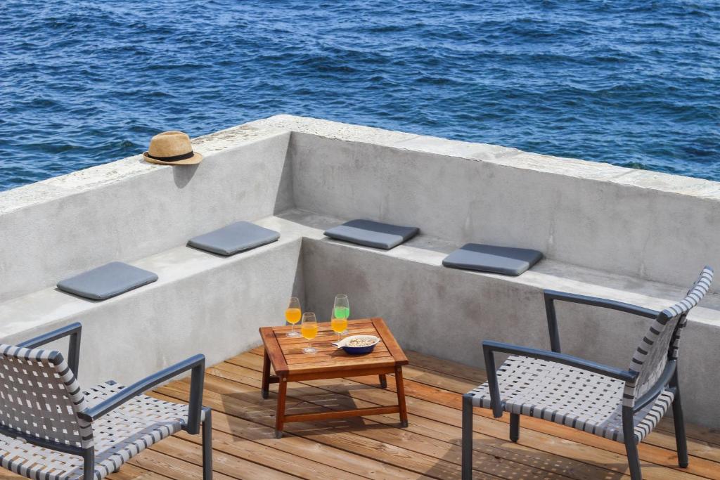 a patio with two chairs and a table on a boat at Maison charmante vue mer - Erbalunga in Erbalunga