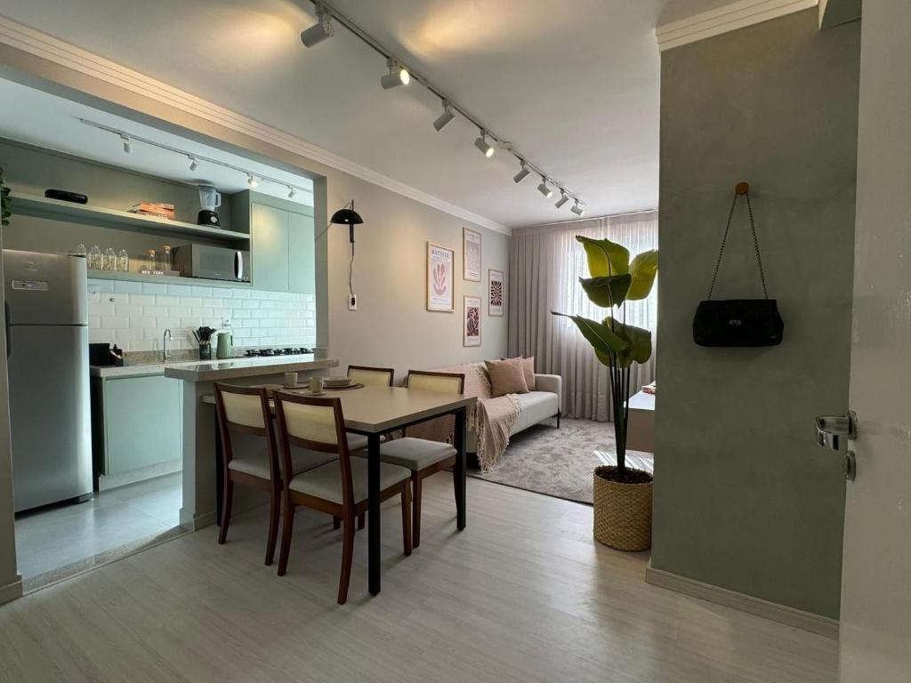 Una cocina y una sala de estar con mesa y sillas. en Apartamento moderno próximo ao SESC, en Franca