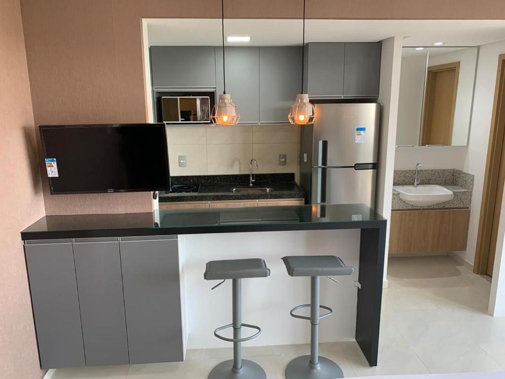 uma cozinha com um balcão com bancos e uma geladeira em Flat Studio São Luís em São Luís