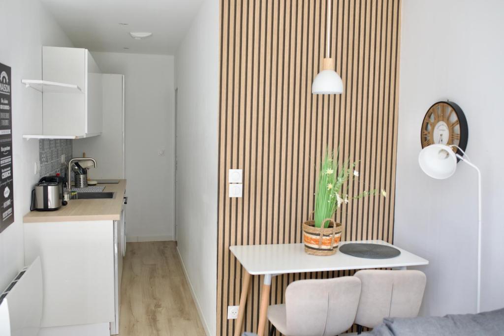 une cuisine avec une table et deux chaises blanches dans l'établissement T2 Cosy proche parc de la Hotoie, à Amiens