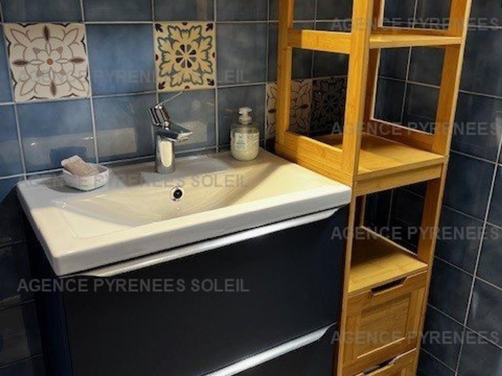 La salle de bains est pourvue d'un lavabo et d'une étagère. dans l'établissement Charmant T2 lumineux avec loggia et coin cabine - Bien équipé - FR-1-295-190, aux Angles