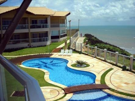 a view of a resort with a swimming pool and the ocean at EmanuelleSales - Corretora de Imóveis - "LUXURY RESIDENCES" creci 16949F in Canoa Quebrada
