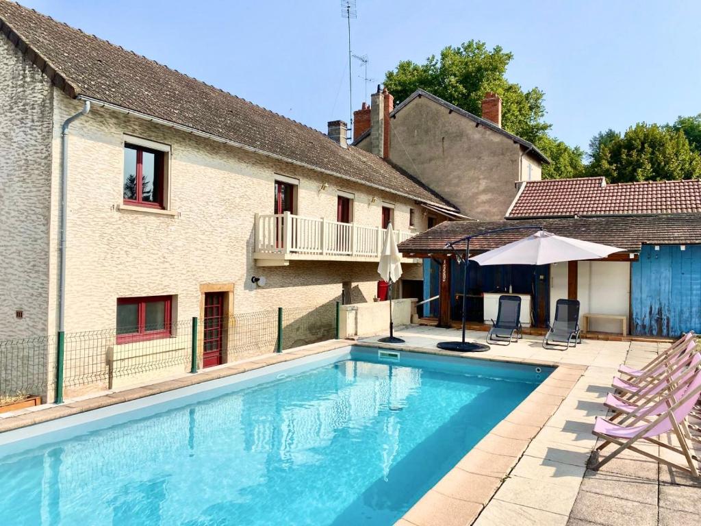 - une piscine à côté d'un bâtiment avec un parasol dans l'établissement Maison cosy avec piscine, à Paray-le-Monial