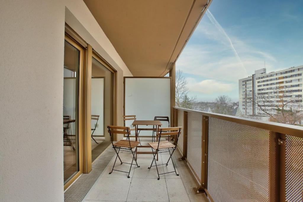 un balcón con mesa y sillas. en Chambre privée dans un appartement en colocation, parking gratuit, en Bagneux