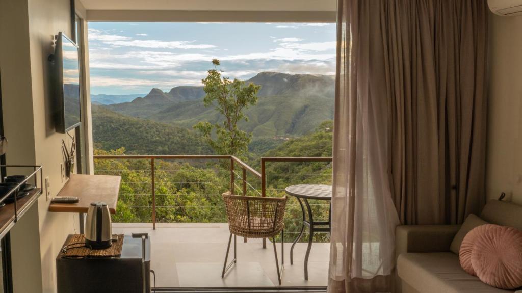 ein Zimmer mit Balkon und Blick auf die Berge in der Unterkunft Calliandra Suítes Minimalistas in Alto Paraíso de Goiás