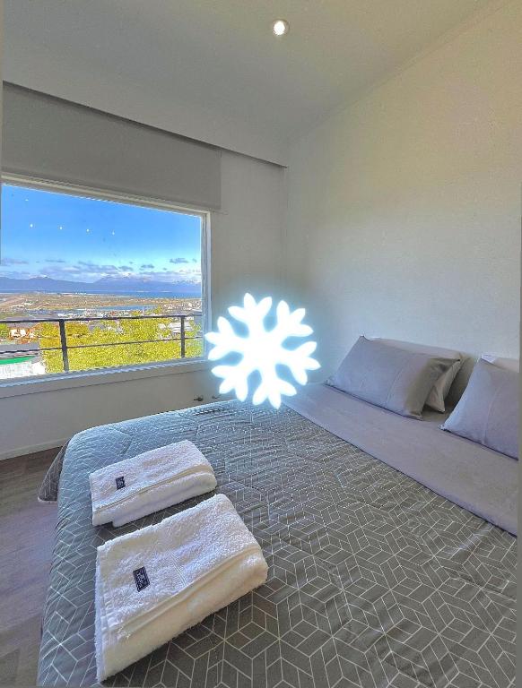 a bedroom with a bed with a large window at Balcón Austral beautiful apartment with incredible views of the mountains and the city in Ushuaia