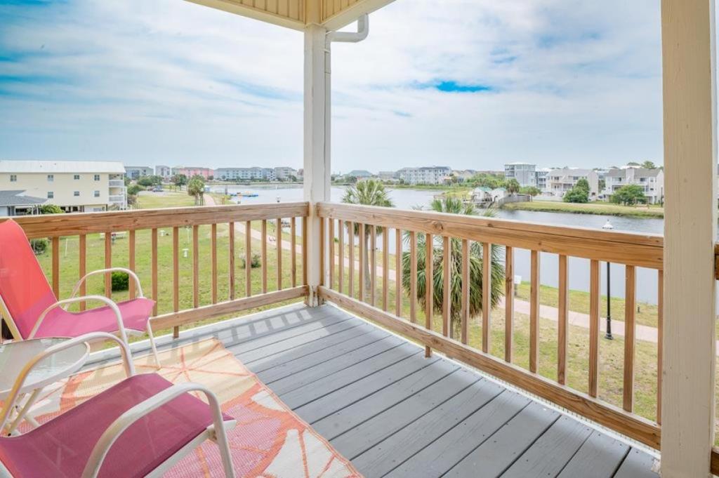 a balcony with chairs and a view of the water at Pelican Pleasure by Sea Scape Properties in Carolina Beach