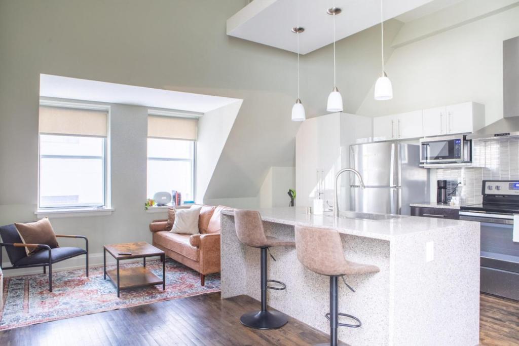 une cuisine et un salon avec un comptoir et des chaises dans l'établissement Downtown Luxury 1BR Loft, à Milwaukee