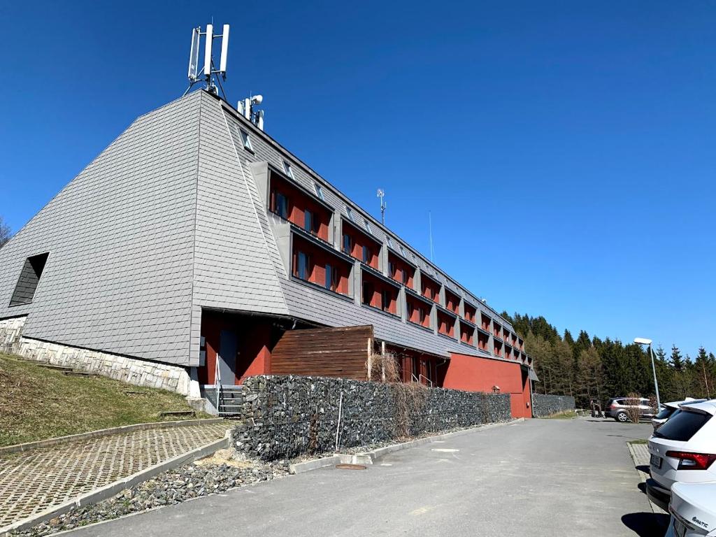 a building with a gray roof with red windows at Apartmán Stratos in Ostružná