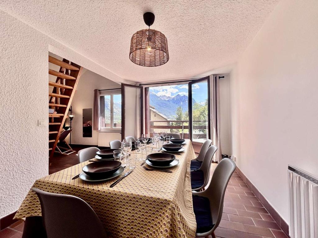 une salle à manger avec une grande table, des chaises et une grande fenêtre dans l'établissement Appartement rénové 4 pièces mezzanine - 8/10 couchages - Proche centre et télécabine, parking - FR-1-330C-145, à Briançon