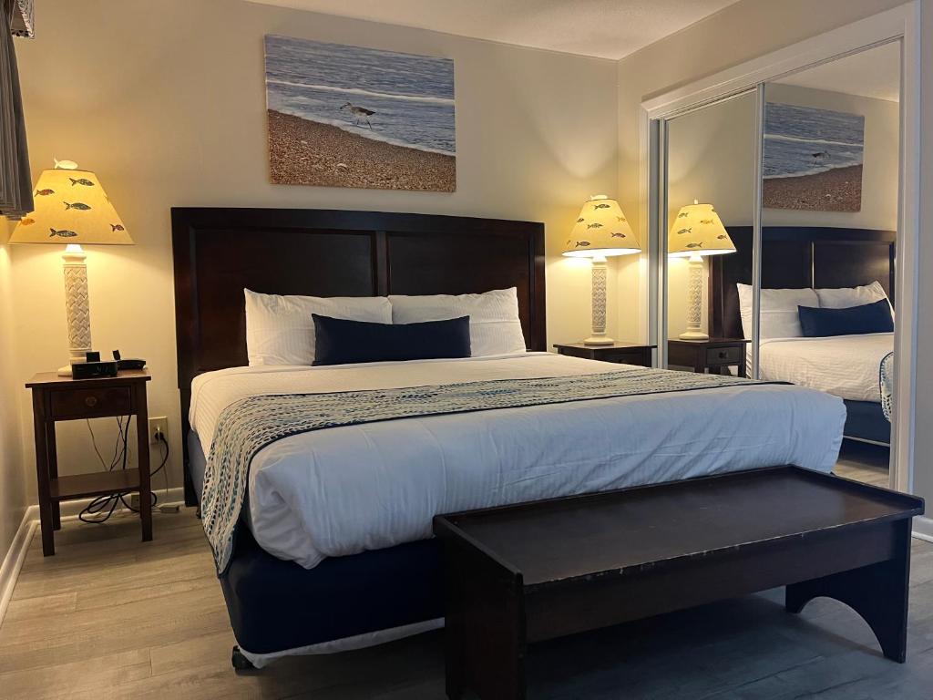 Una habitación de hotel con una cama grande y un espejo. en Summer Sands - 201 by Sea Scape Properties, en Wrightsville Beach