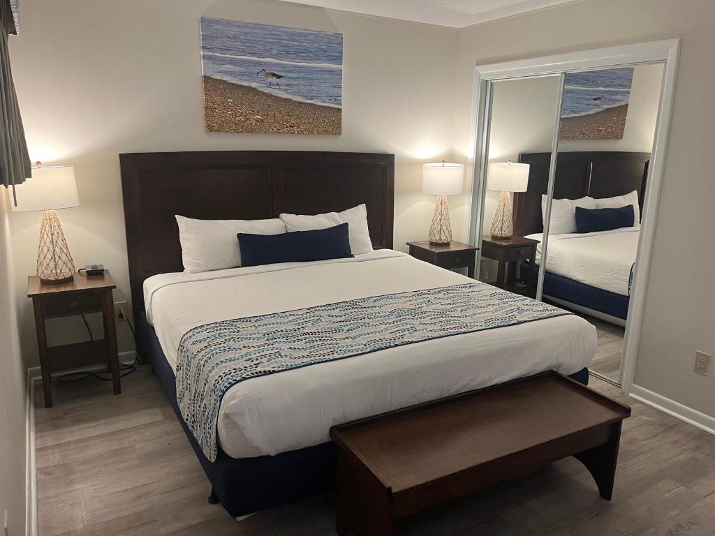 a bedroom with a bed and two lamps and a mirror at Summer Sands - 307 by Sea Scape Properties in Wrightsville Beach