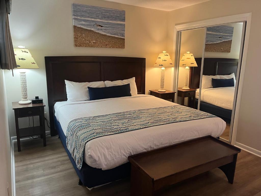 a bedroom with a bed and two lamps and a mirror at Summer Sands - 401 by Sea Scape Properties in Wrightsville Beach