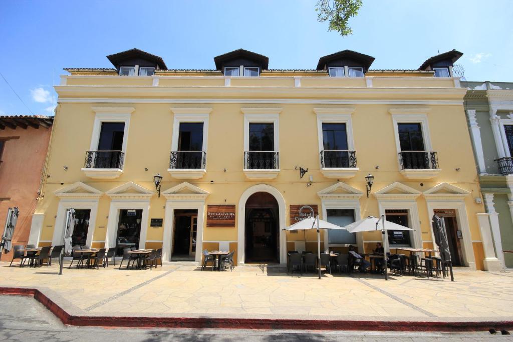 a building with tables and umbrellas in front of it at Hotel Ciudad Real Centro Historico in San Cristóbal de Las Casas