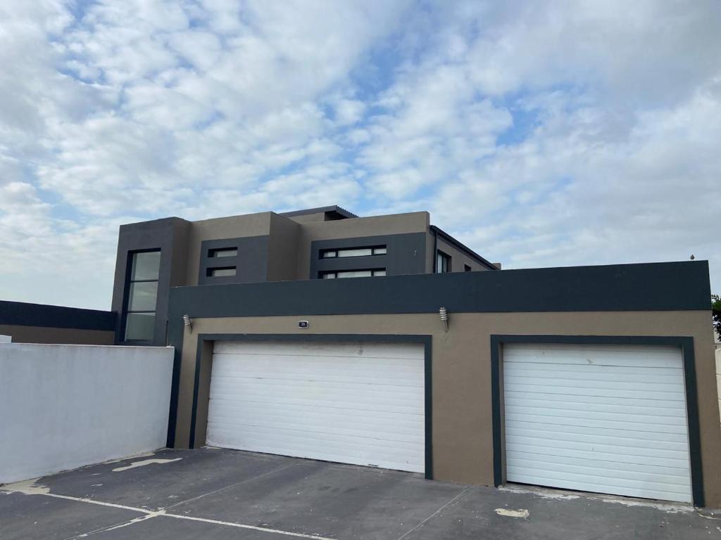 ein Gebäude mit zwei Garagentüren davor in der Unterkunft Cottage on 36 Neethlingshof in Kapstadt