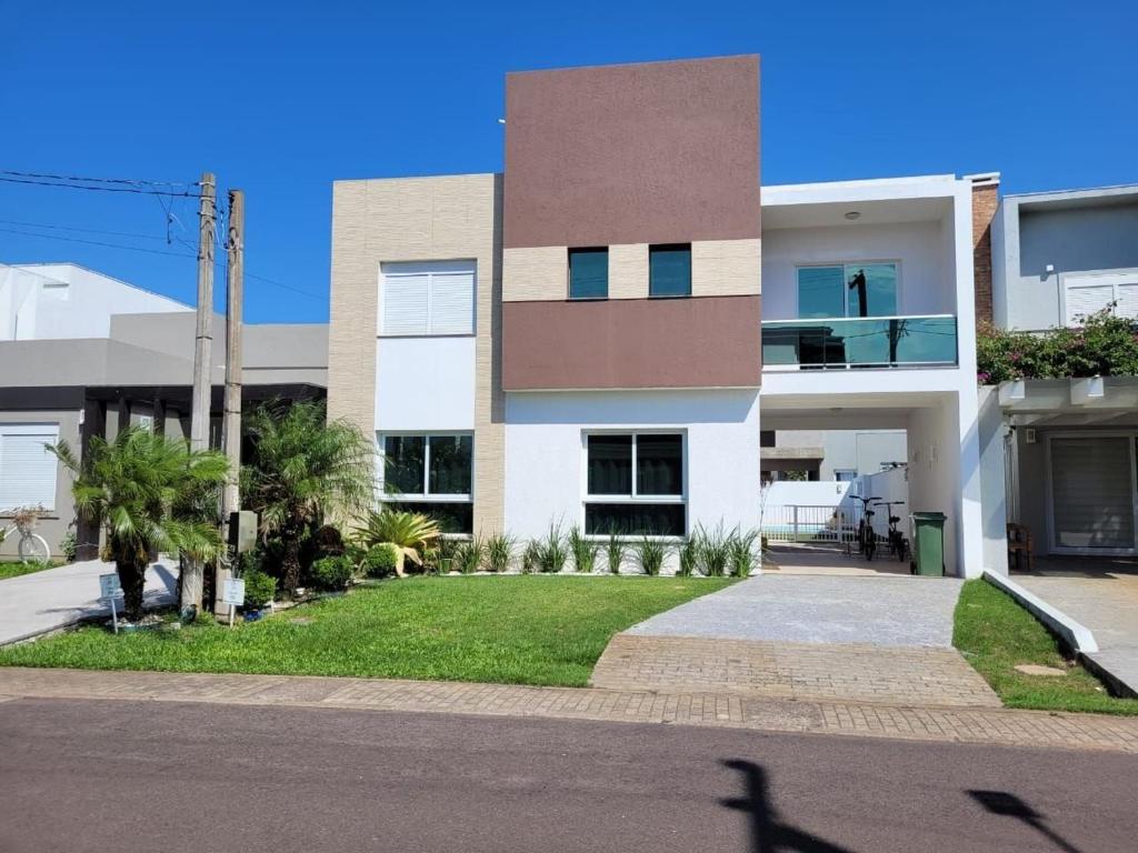 un grand bâtiment blanc avec des palmiers devant dans l'établissement Casa de Verão dos Sonhos no Las Palmas, à Xangri-lá