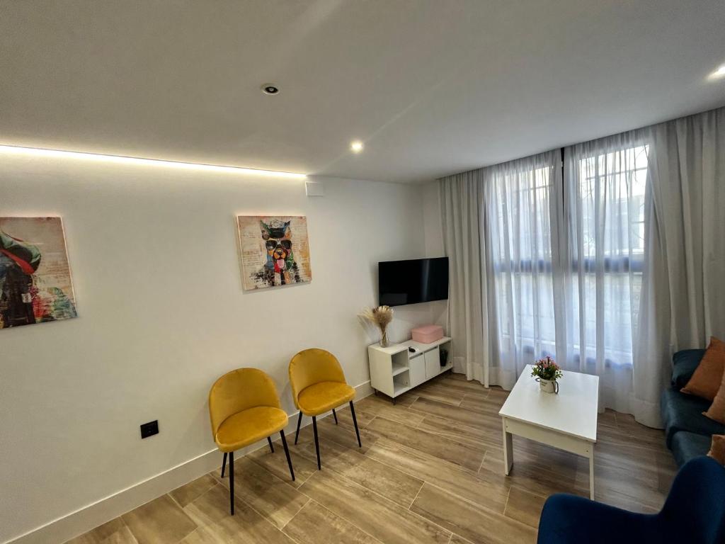 a living room with yellow chairs and a couch at BAJO A habitación con literas Apartamentos JUAN ROBLEDO Centro Ciudad in Andújar