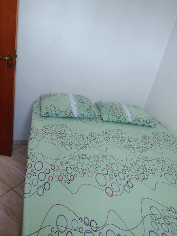 a bed with a green comforter and pillows at Apartamento avenida 06 com ar condicionado in São Thomé das Letras