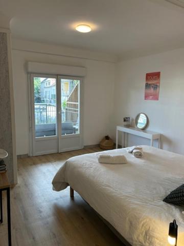a white bedroom with a bed and a window at Loft avec parking centre Tours et bord du Cher Loire Valley in Tours