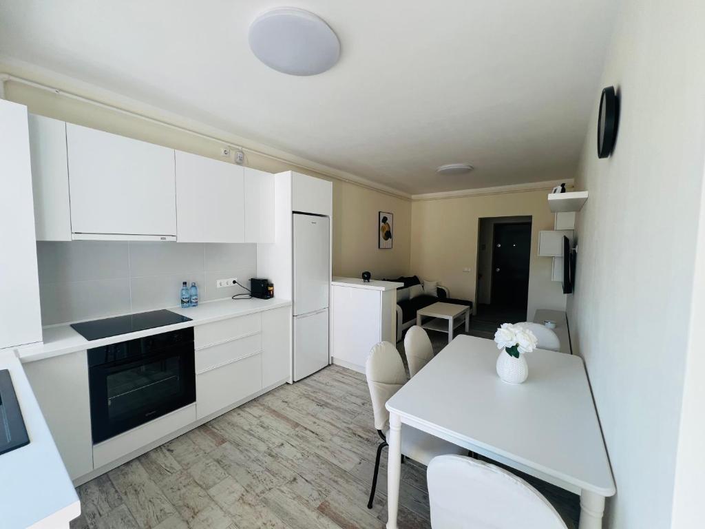 Una cocina con gabinetes blancos y una mesa con sillas. en Ivy Central Residence, en Baia Mare