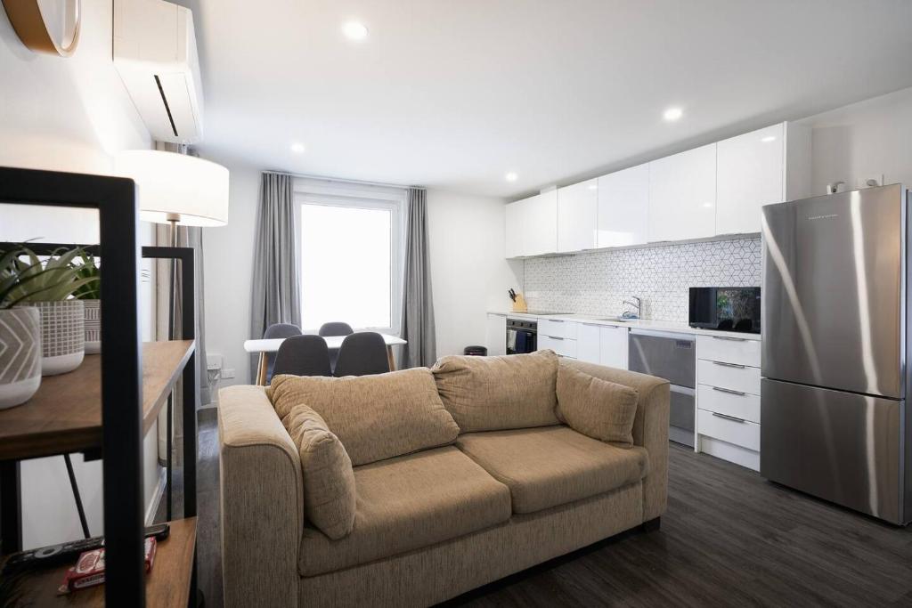 a living room with a couch and a kitchen at Modern Central Apartment, Flexible Bed Options in Dunedin