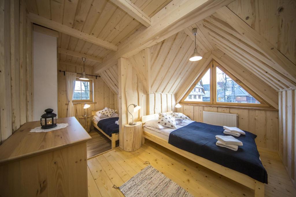 ザコパネにあるDomek Tatryの木造キャビン内のベッドルーム1室(ベッド2台付)