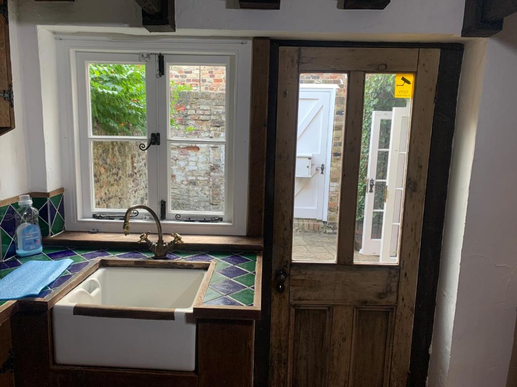 a kitchen with a sink and a door with windows at Quay Cottage in Sandwich, UK in Sandwich