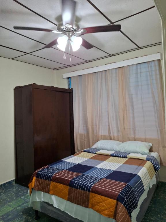 Un dormitorio con ventilador de techo y una cama. en Hostal primaveras nest, en Santa Ana