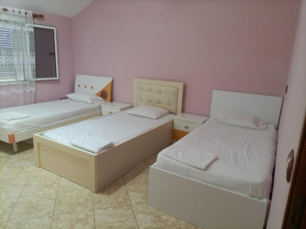 two beds in a room with pink walls at Villas Eleni for rent best view in Xhafzotaj