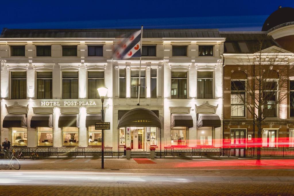 a white building with a flag on the front of it at Post-Plaza Hotel & Grand Café in Leeuwarden
